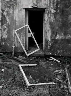 A frame of a door on an old delapitated house lies on the floor